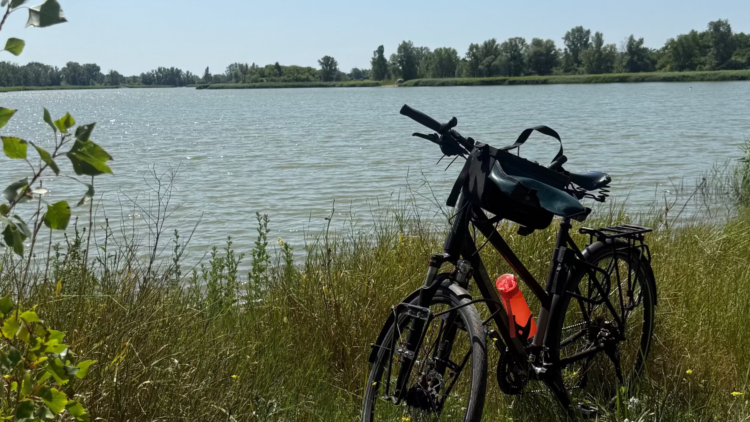 Trekkingrad mit Lenkertasche an idyllischem See – nachhaltige Mode für radbegeisterte Frauen im Alltag